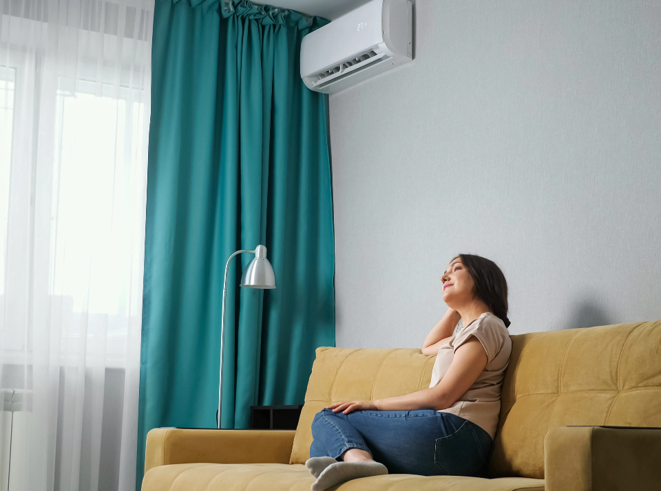 side-view-brunette-woman-adjusts-air-conditioner-while-sitting-sofa